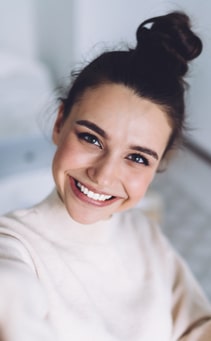 Pretty young female with big smile standing at bedroom