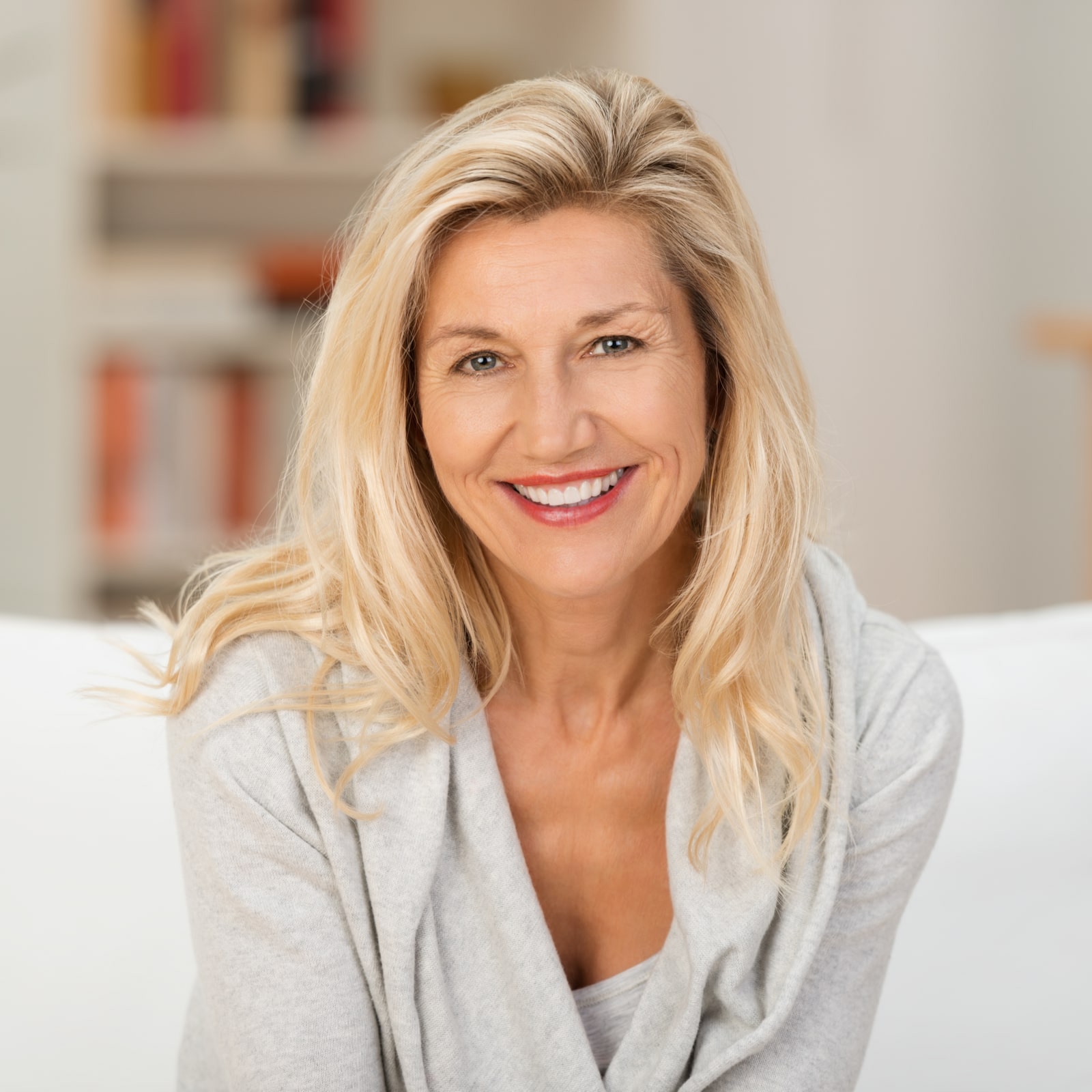 blond woman with a beaming smile sitting on a sofa