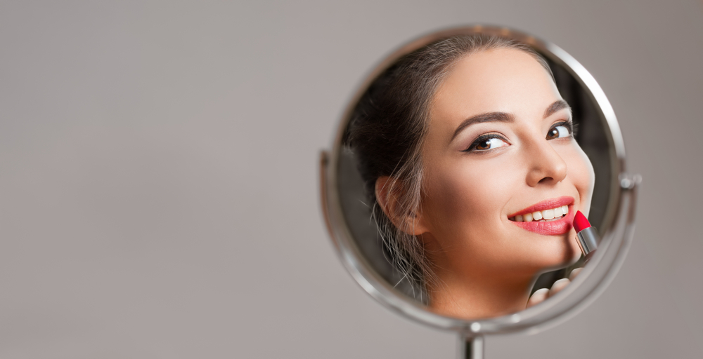 A woman smiling in the mirror after taking advantage of Preventative Dentistry