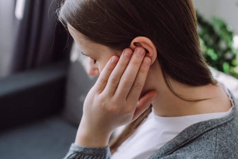 Woman touching her left ear possibly suffering from Sudden Hearing Loss