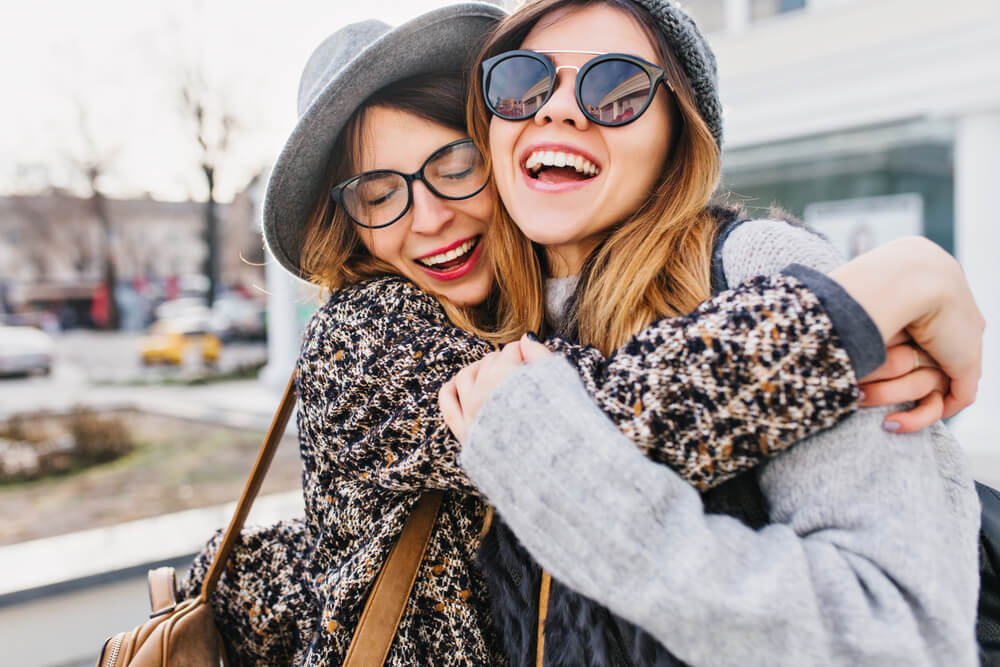 happy girls hugging on street in city
