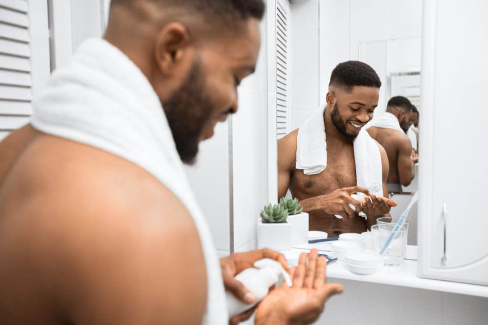 smiling man squeezing cream on his hand