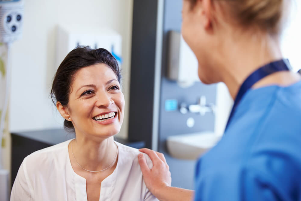 Female Patient Being Reassured By Doctor In Hospital