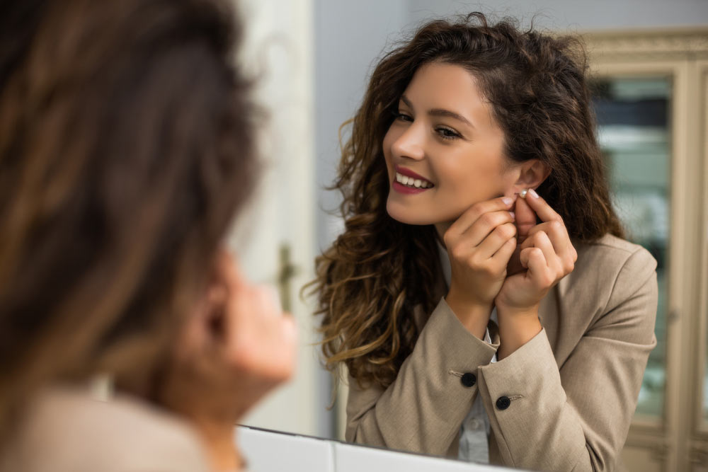 women is putting earrings while preparing for work