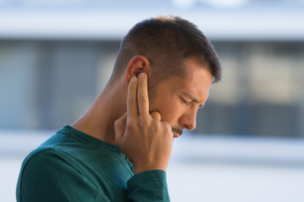 Man touching his ear due to possible hearing loss