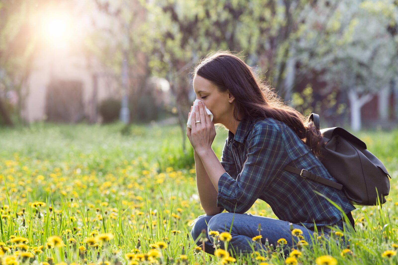 woman sitting in a field of flowers blowing her nose