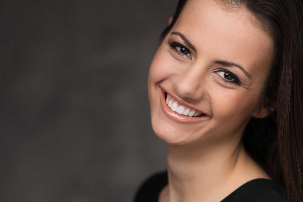 Women smiling at the camera after receiving an AviClear treatment for her moderate acne