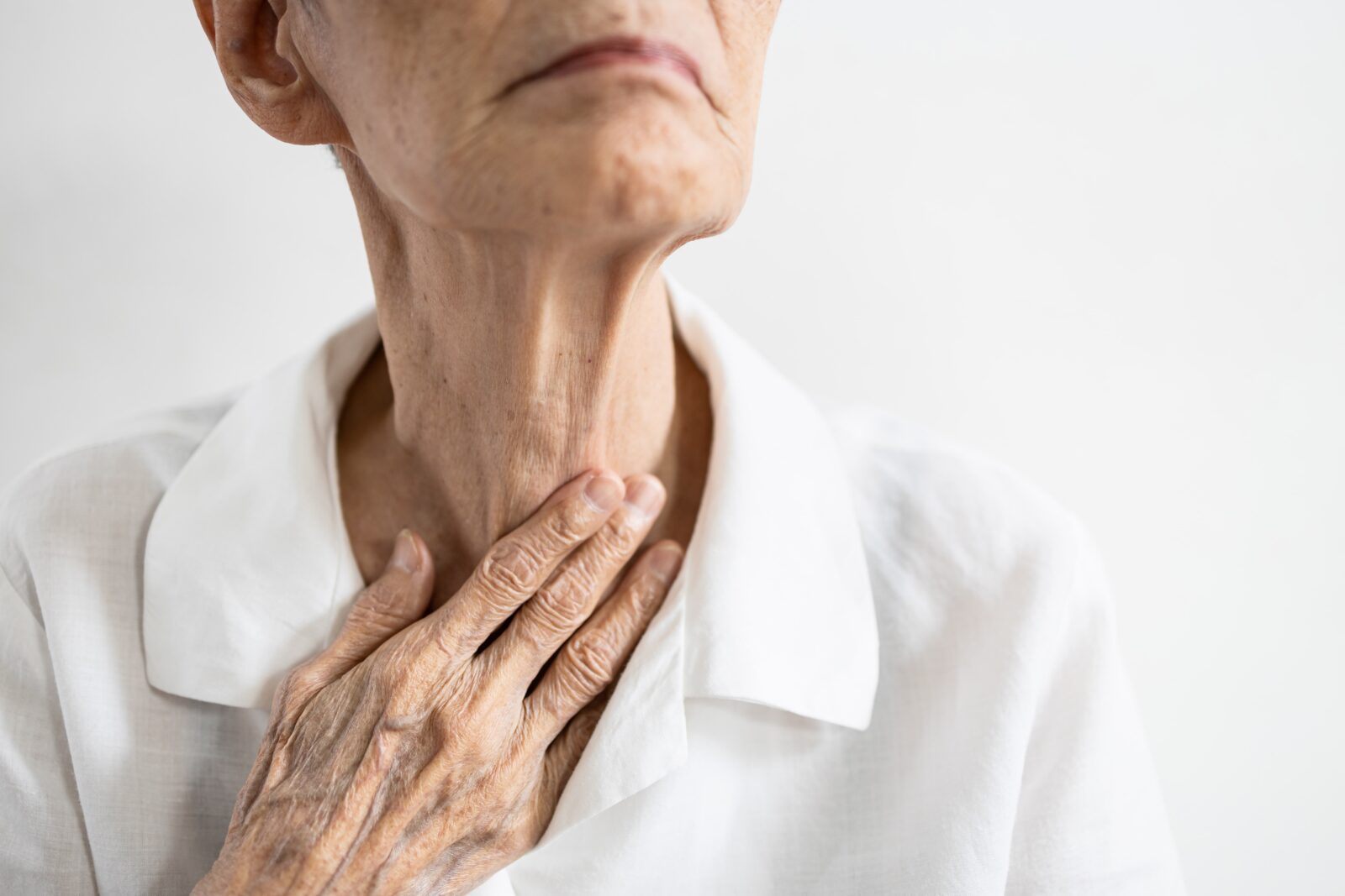 Asian senior patient touching neck with her hand,old elderly has sore throat,foreign body stuck in throat,painful swallowing,pain cough,inflammation of the larynx,throat problems or laryngitis disease
