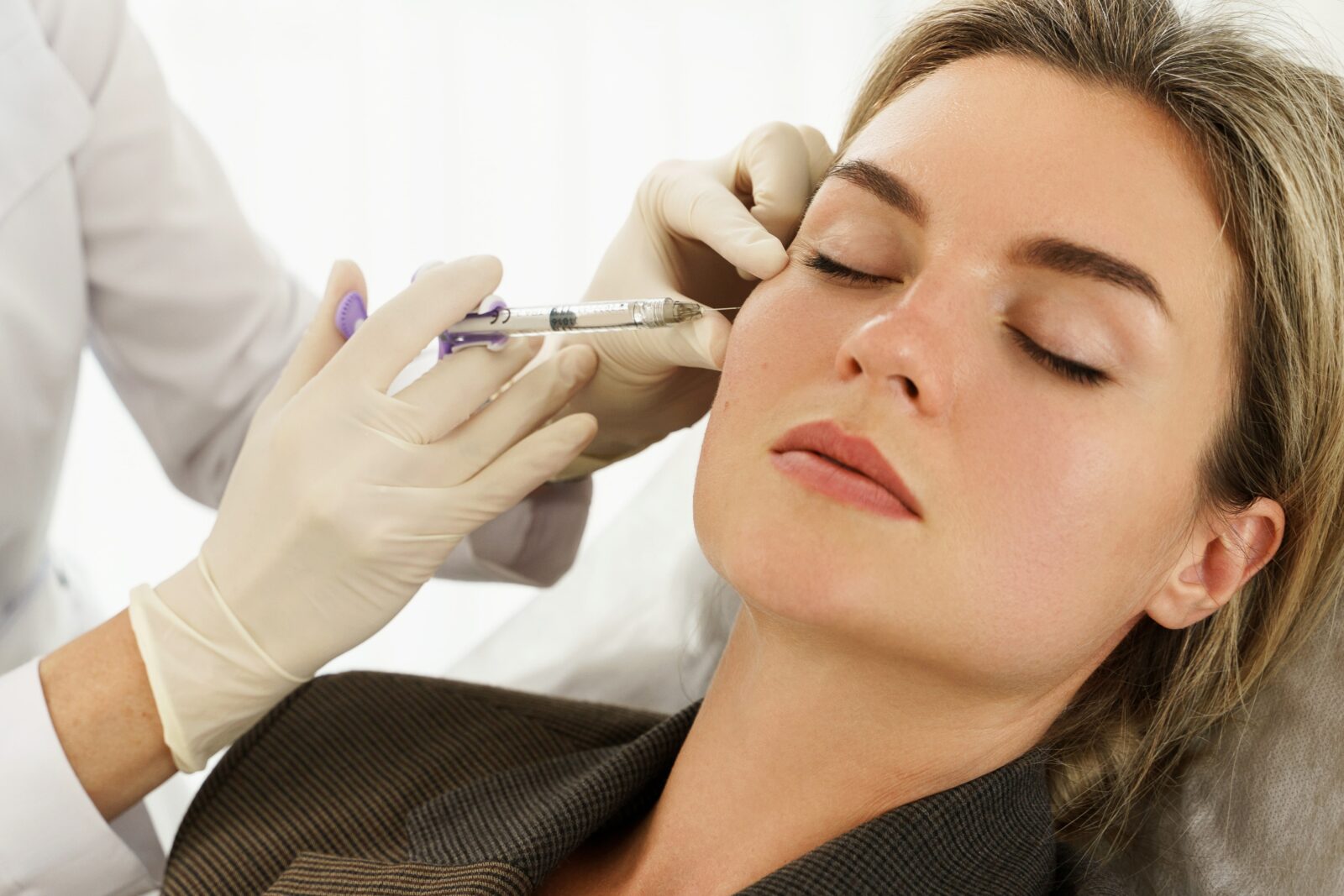 Female client during facial filler injections in aesthetic medical clinic