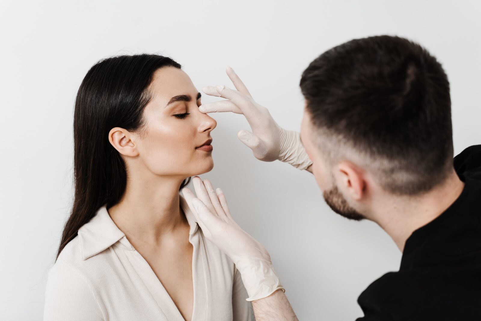 ENT doctor is touching nose and consulting girl patient in medical clinic before septoplasty surgery. Rhinoplasty is reshaping nose surgery for change appearance of the nose and improve breathing
