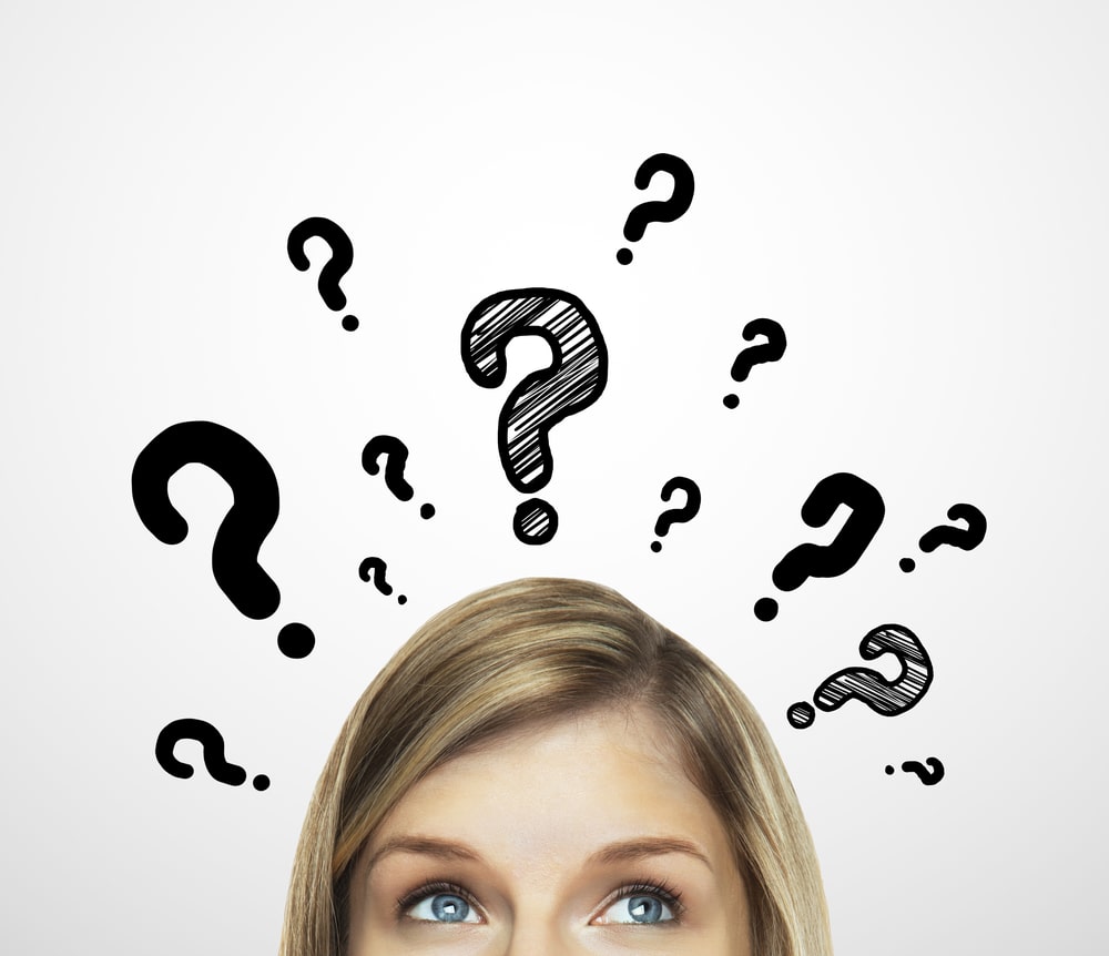 top half of woman's face surrounded by question marks