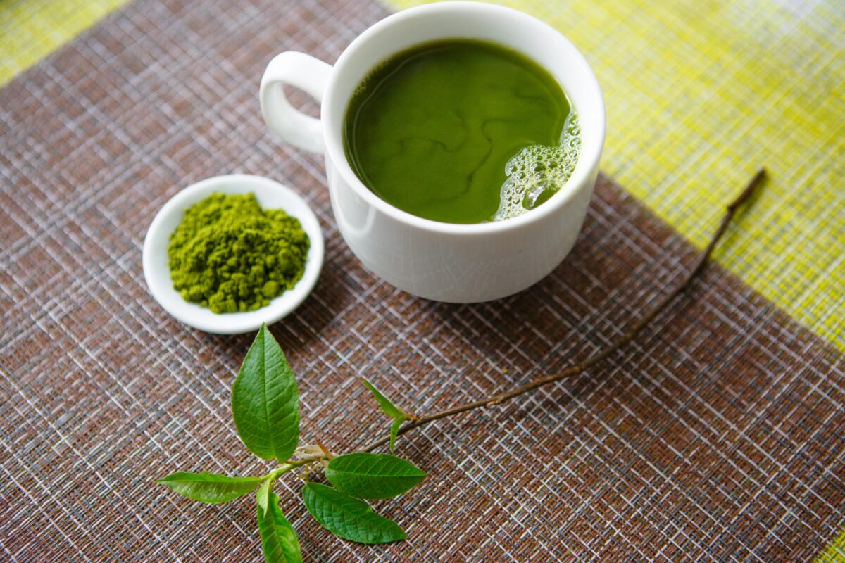 matcha powder besides a cup of green tea