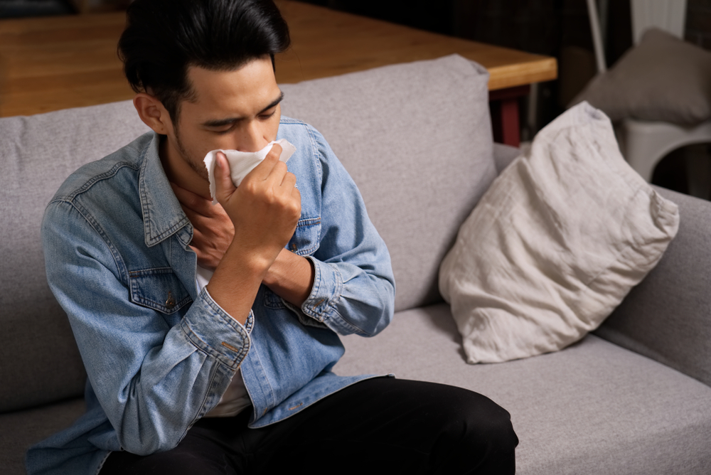 man coughing to clear the throat with hand holding tissue paper