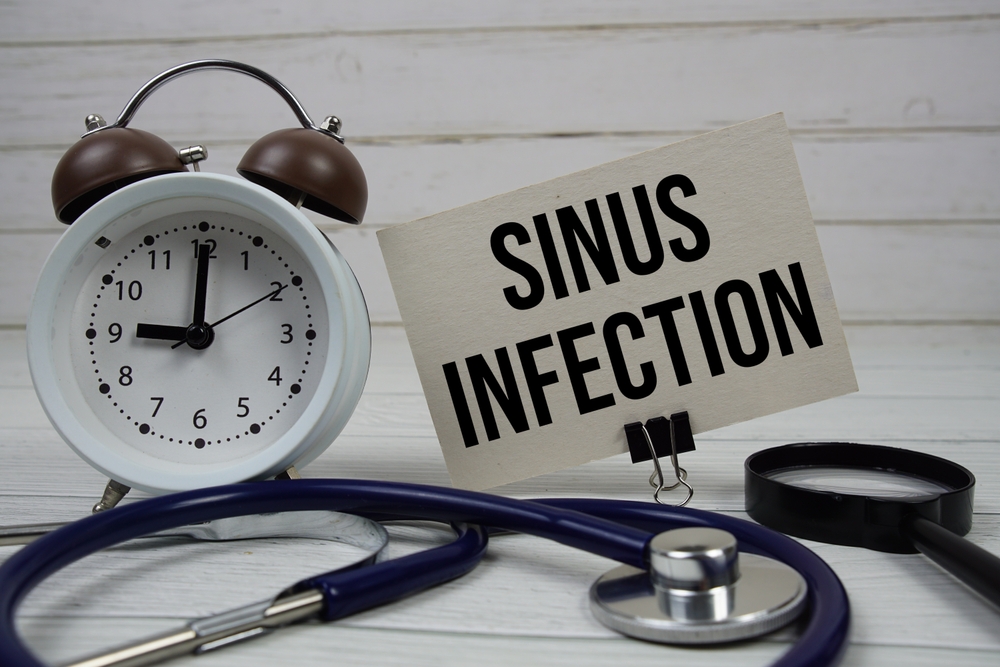 Sinus Infection text message on paper card with stethoscope and alarm clock on wooden background