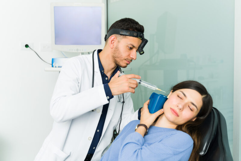 Distressed young woman getting her ears cleaned