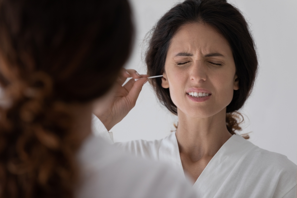 Head shot unhappy millennial hispanic latina woman using cotton bud or stick, cleaning ears after shower
