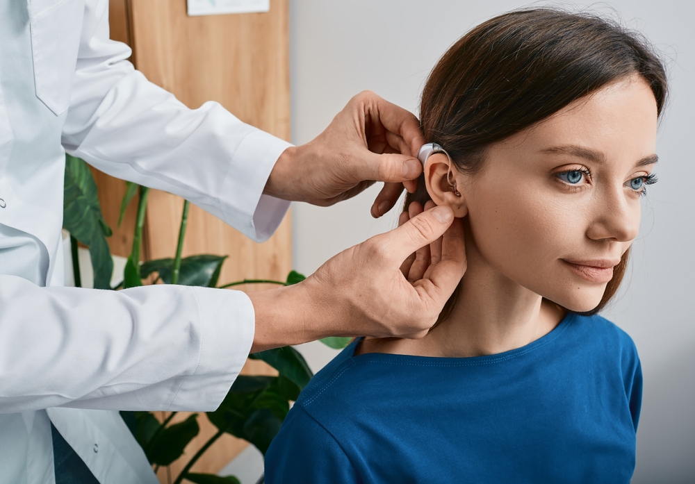 Installation hearing aid on woman's ear at hearing clinic