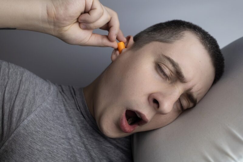 The man puts on earplugs. Close-up of an orange noise barrier. Deep sleep. The ENT doctor advises orange