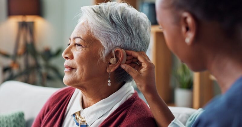 Nurse, woman and hearing aid on ear for medical support, wellness and innovation of disability.