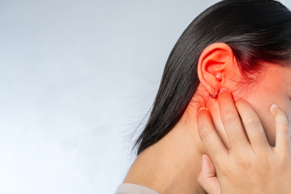 Young woman suffering from ear pain and tinnitus