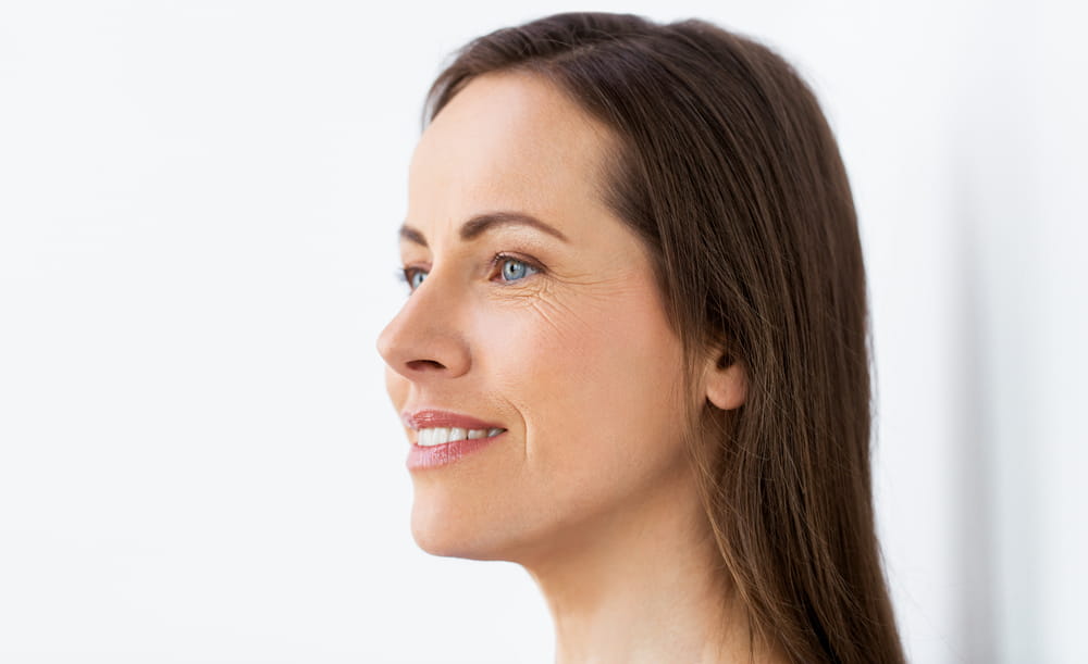 health and beauty concept - side view of happy smiling middle aged woman face