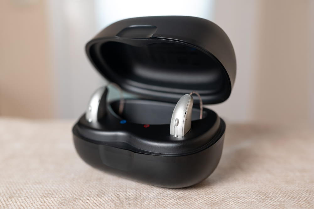 Modern hearing aids charging in a black opened case