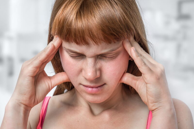 Woman with headache or migraine is holding her aching forehead - body pain concept