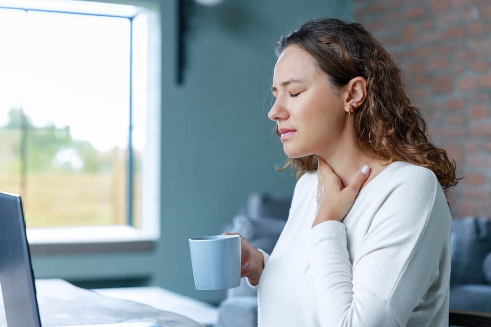 Young freelancer business woman with sore throat working with laptop pc in living room at home