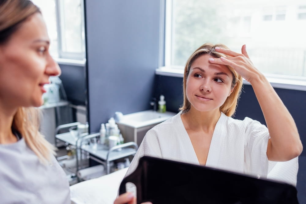 Doctor checking woman face skin in cosmetology clinic before plastic surgery. Surgeon or beautician touching woman face.