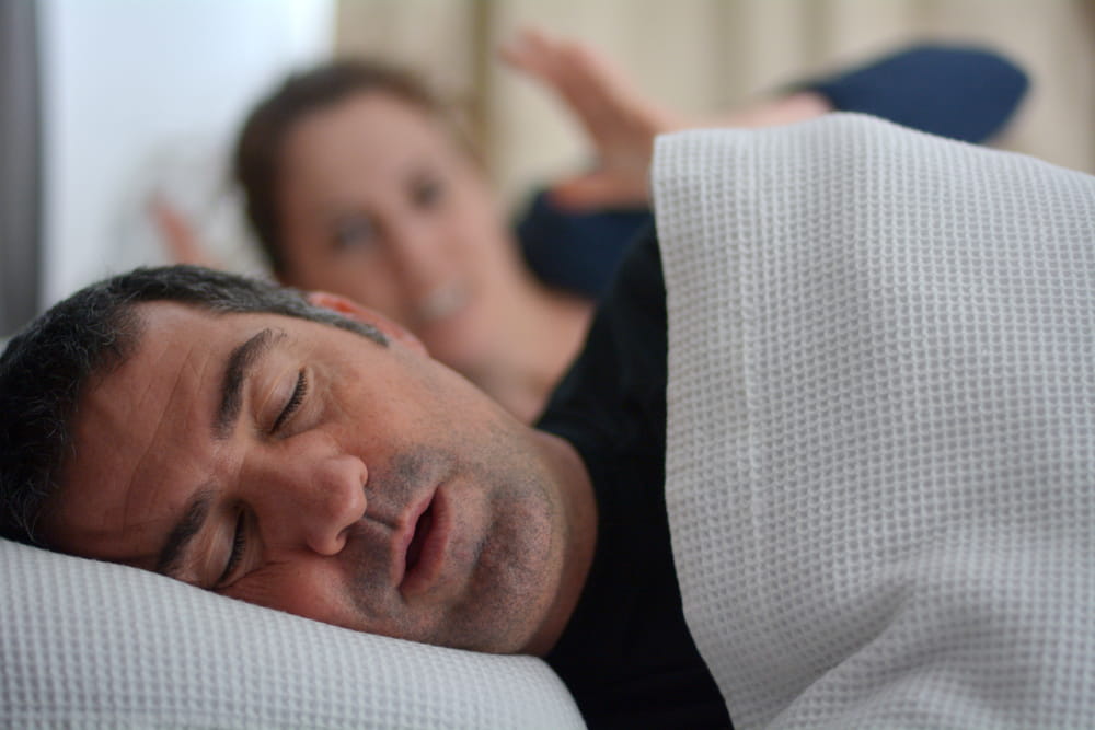 Woman (female age 30) suffers from her male partner (man age 40) snoring while lying in bed together