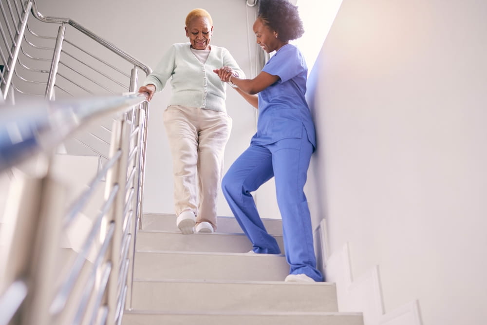 Steps, nurse and help elderly woman, holding hands and assistance in home.