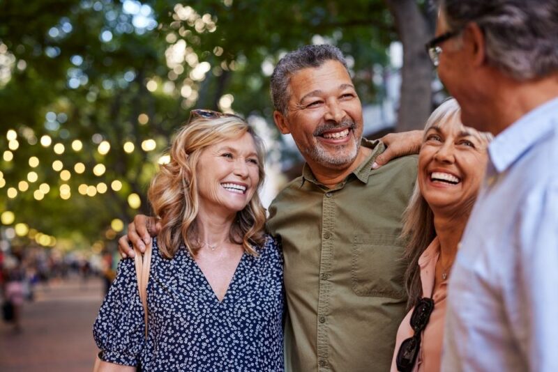 Group of happy senior friends sharing a moment outdoor while embrace.