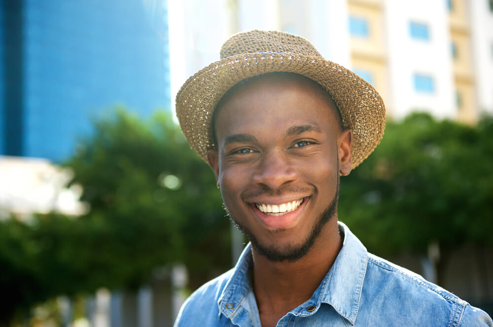 trendy young man smiling with hat