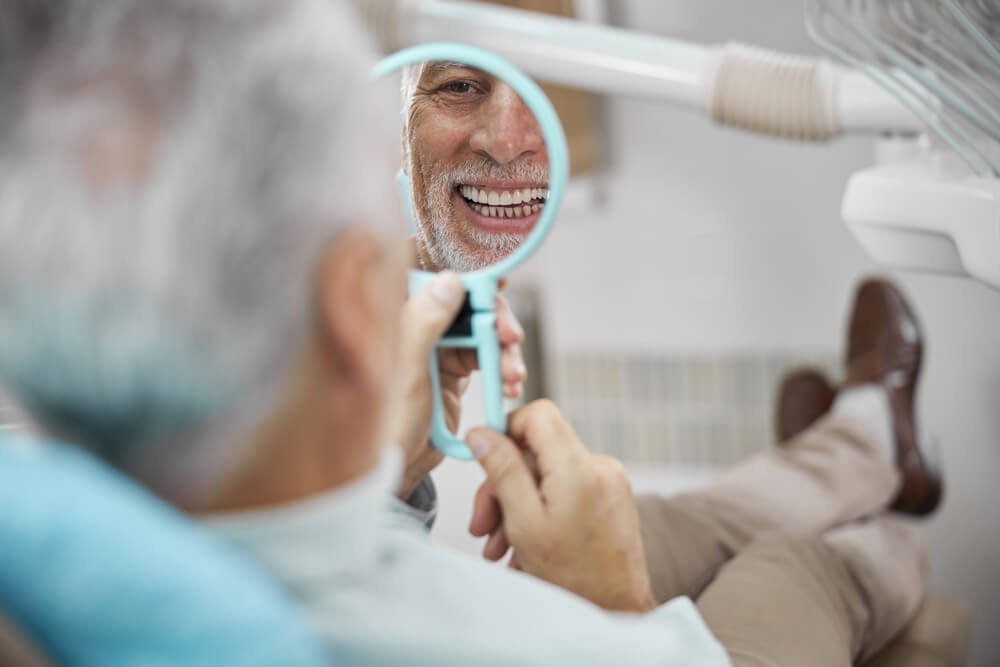 Aged patient sitting in a dental chair looking in the mirror
