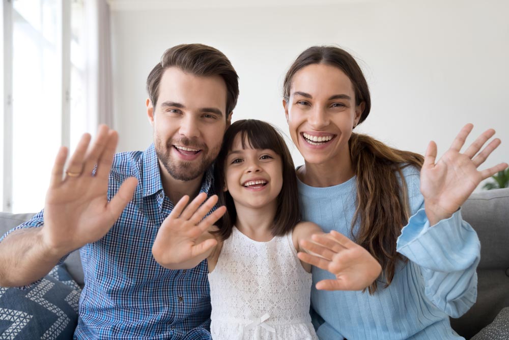 Happy parents sit on couch with cute little daughter