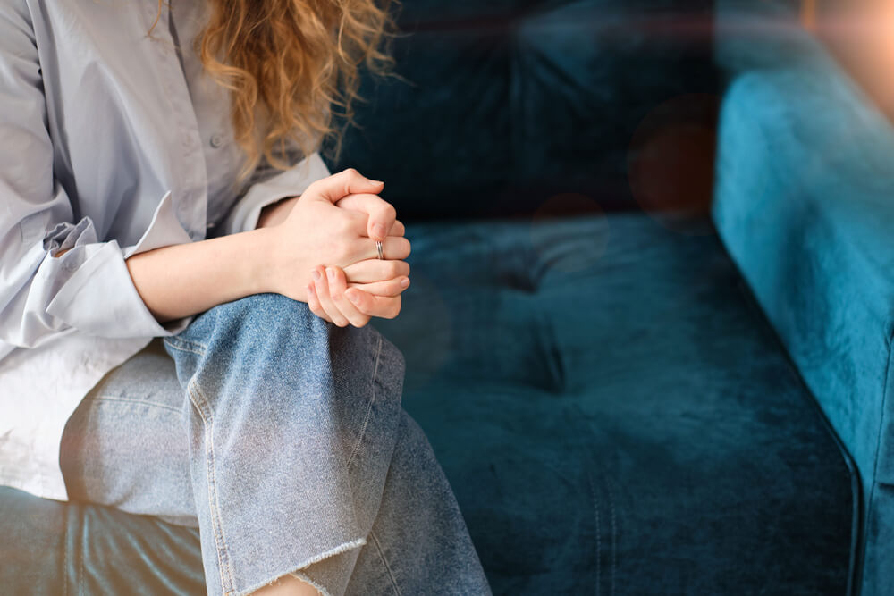 woman clasped her hands to her lap