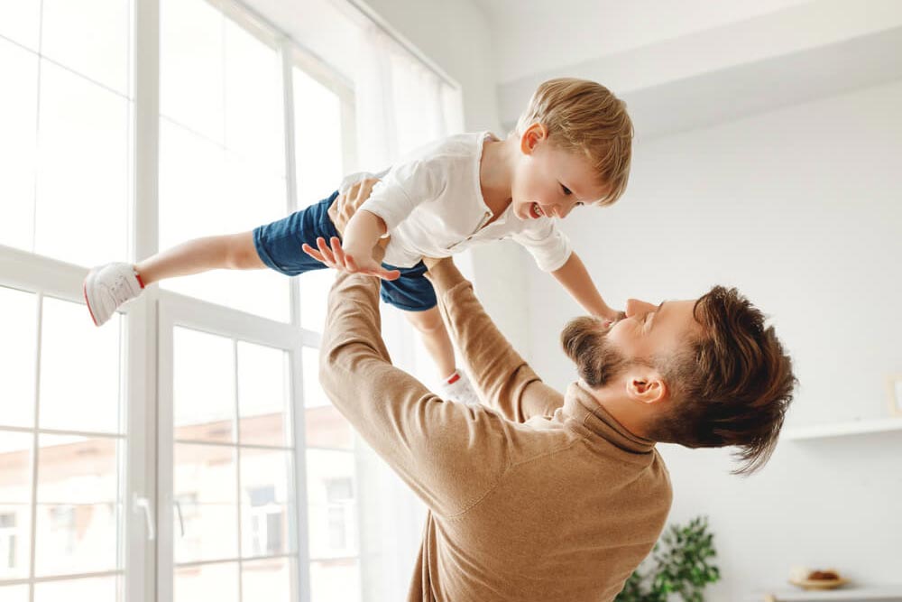 Cheerful young father holding up excited little Son