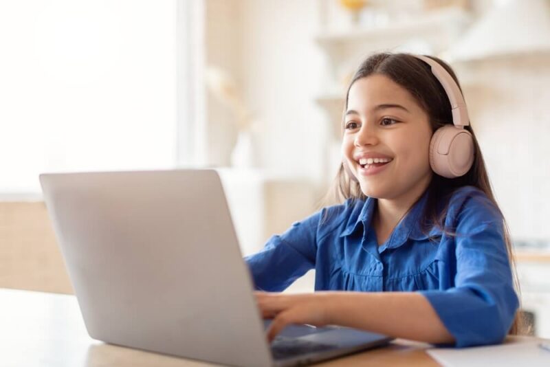 Little Girl Smiling While Using Laptop