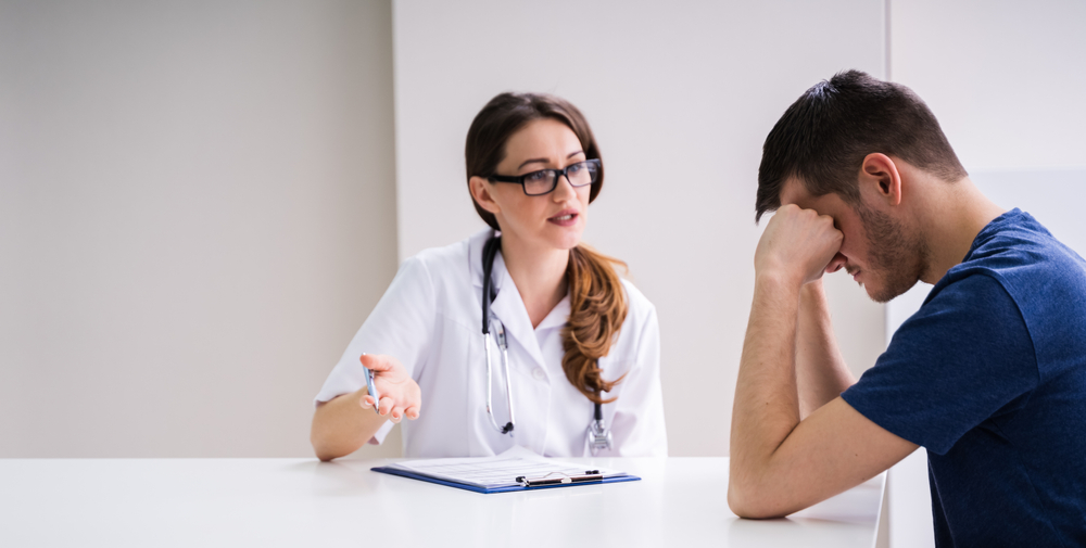 Female Doctor Comforting Depressed Patient Sitting At Table