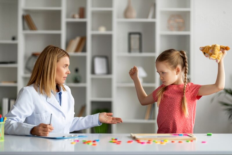 Disobedient bad tempered little girl throwing tantrum at appointment meeting with psychologist
