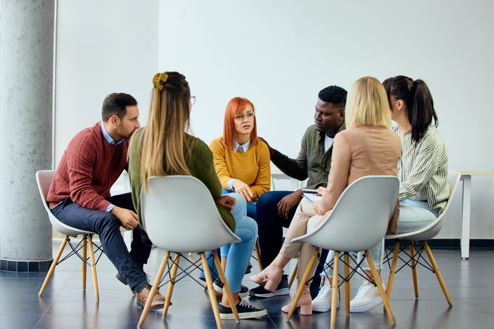 A therapy group in a circle setup providing emotional support and counseling.