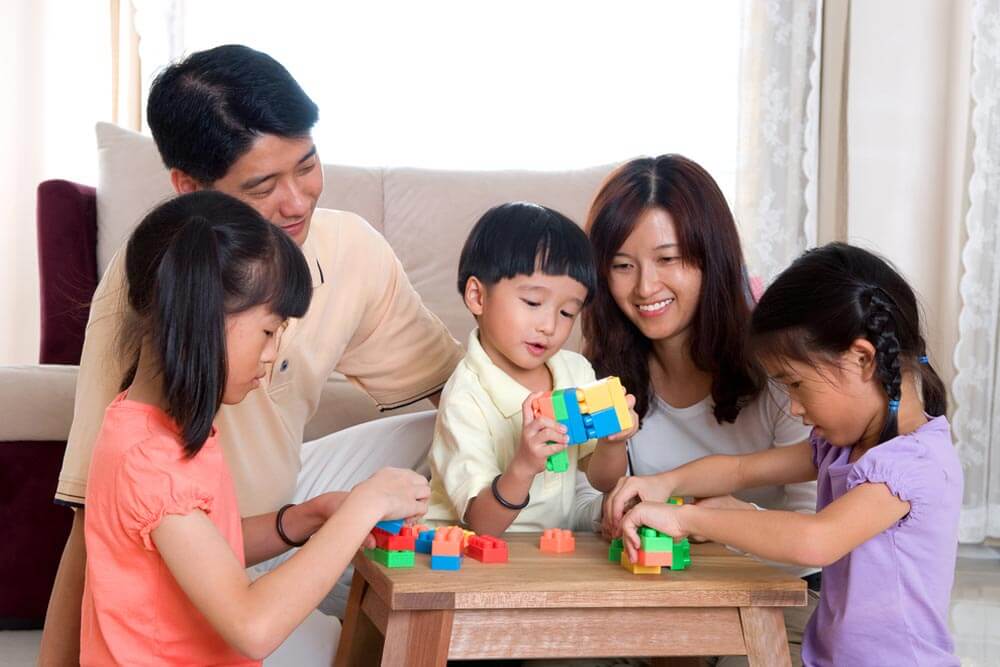 Family with kids playing building blocks