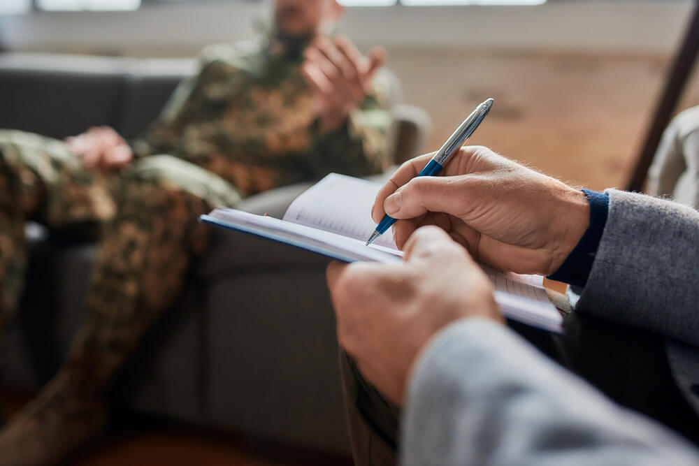 psychologist making notes with military man