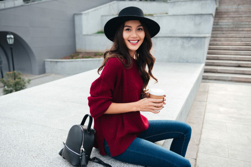 beautiful smiling asian girl wearing hat holding coffee cup