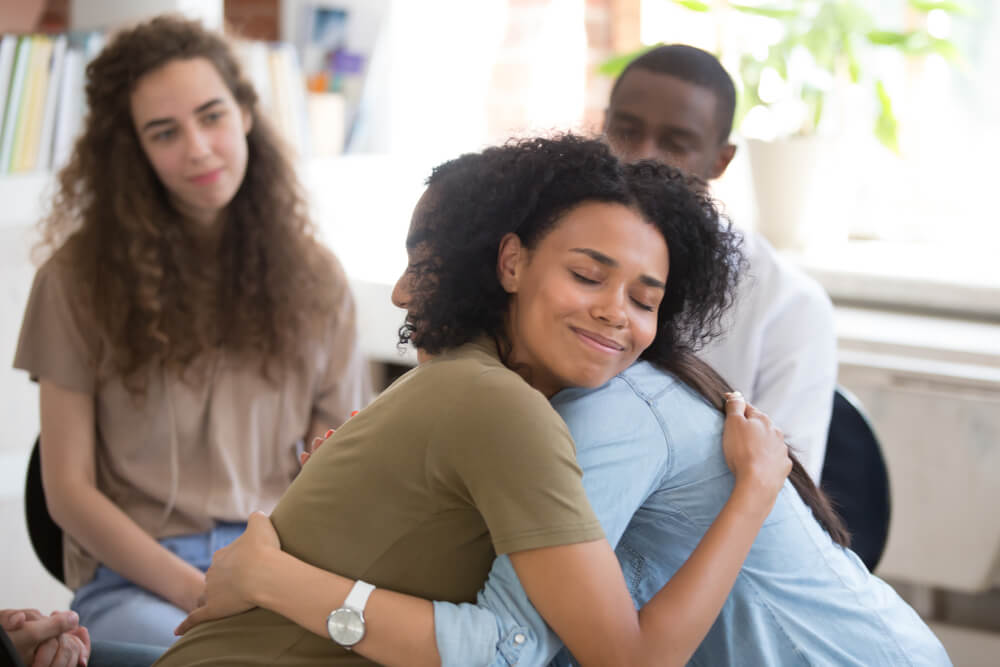 women embracing at group therapy session