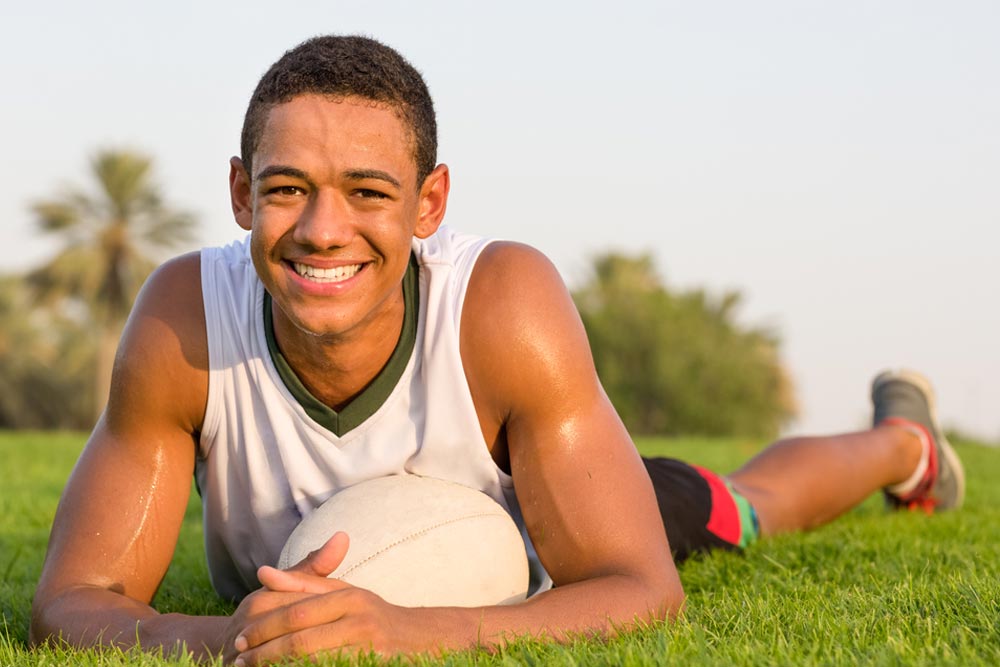 happy fit teen athlete relaxing on the grass