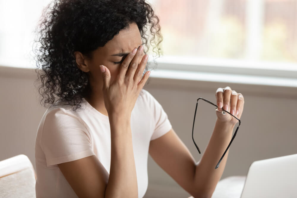 woman dropping eyeglasses, rubbing eyes, feeling exhausted