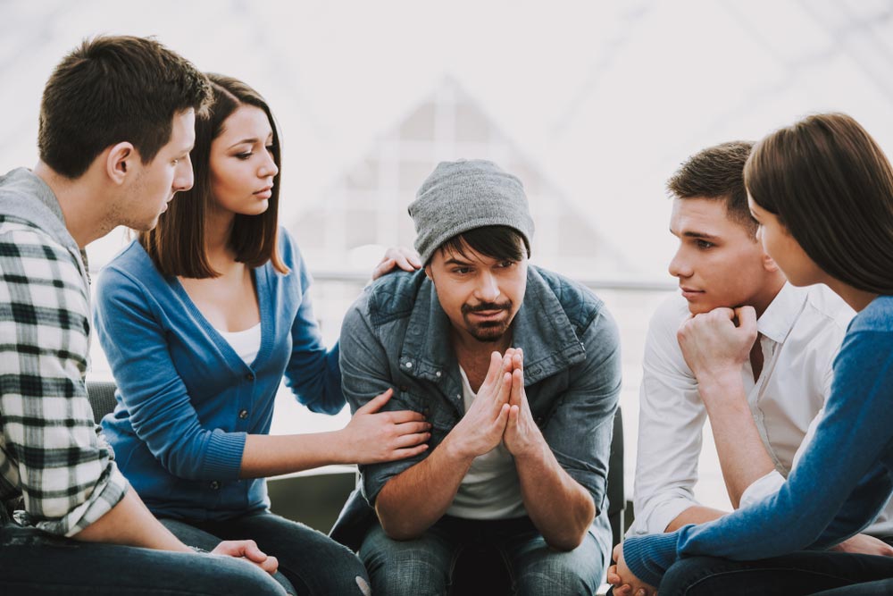 Group of people sitting in circle and supporting each other