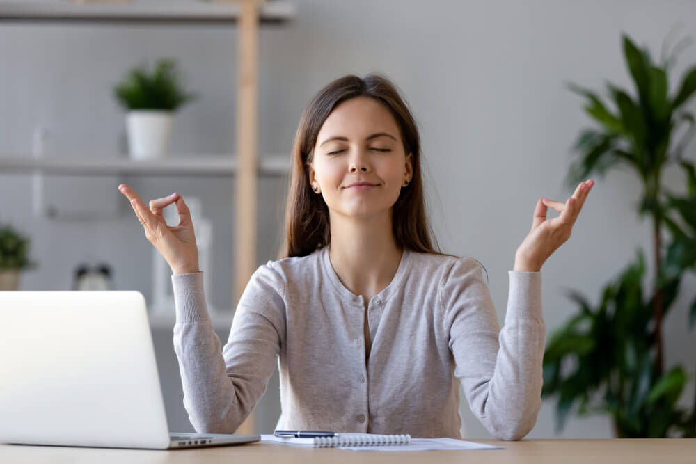 Calm young woman worker taking break doing yoga