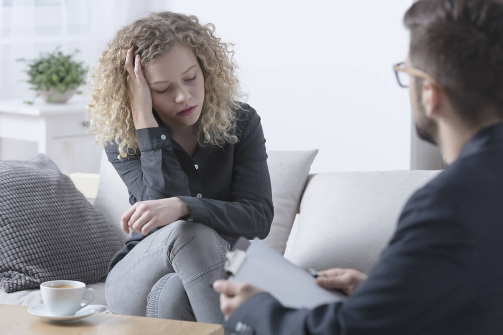 Young worried woman touching her head during psychotherapy